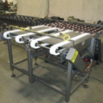 Industrial conveyor automation system with roller table and material handling components in a manufacturing facility.